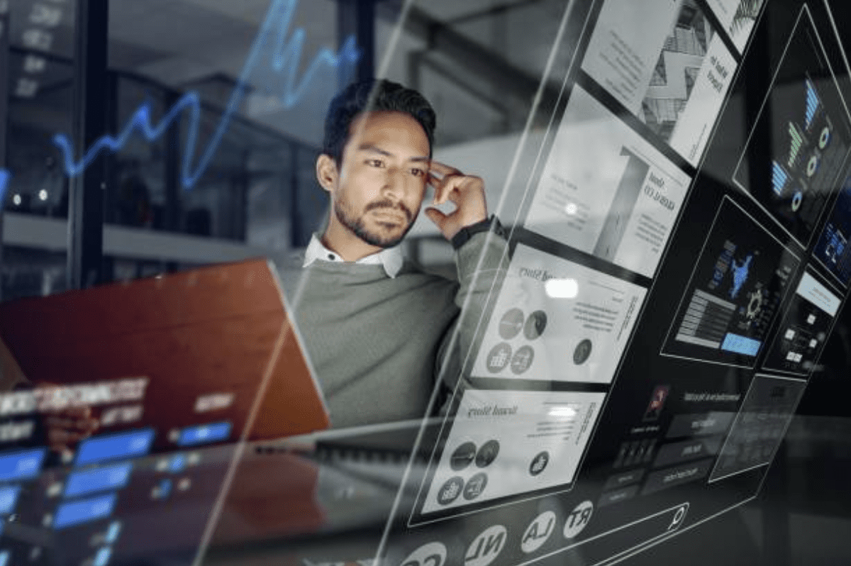 Man at desk using laptop displaying graphs and numerical data